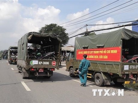 Lực lượng kiểm soát quân sự vận chuyển xe máy cho người dân lên xe ôtô chở về quê. (Ảnh: TTXVN phát)