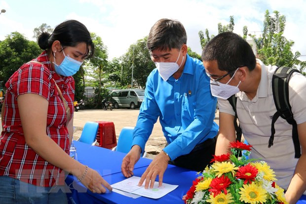 Ông Phạm Chí Tâm, Phó Chủ tịch Liên Đoàn Lao động Tp. Hồ Chí Minh hướng dẫn đoàn viên nghiệp đoàn có hoàn cảnh khó khăn về việc tham gia bảo hiểm xã hội. (Ảnh: Thanh Vũ/TTXVN)