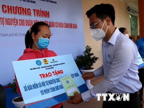 Lãnh đạo Quận ủy quận Tân Phú trao sổ bảo hiểm cho đoàn viên nghiệp đoàn có hoàn cảnh khó khăn ở quận Tân Phú. (Ảnh: Thanh Vũ/TTXVN)