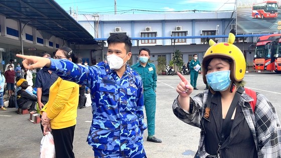 Người dân được cán bộ chiến sĩ hướng dẫn để lên xe về quê. Ảnh: VĂN MINH