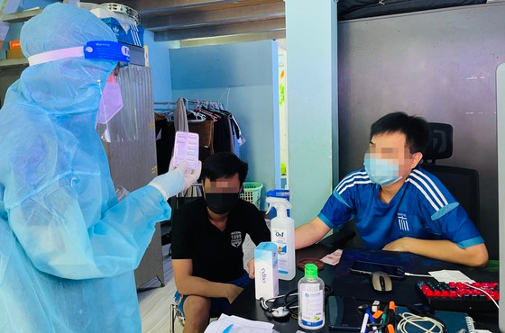 Cán bộ y tế đến nhà thăm khám và cấp phát các túi thuốc cho người mắc Covid-19. Ảnh: VĂN MINH