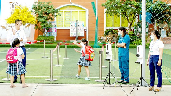 Học sinh Trường Tiểu học Lê Đức Thọ (quận Gò Vấp) hoàn tất thủ tục phòng dịch trước khi vào trường. Ảnh: HOÀNG HÙNG