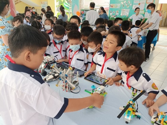 Ngô Hoàng Đạt, học sinh lớp 1/2 (thứ hai từ phải qua) hào hứng khoe với bạn về những trải nghiệm khi điều khiển robot thông qua thiết bị ipad