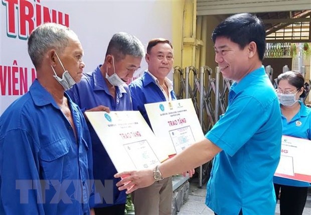 Ông Phạm Chí Tâm, Phó Chủ tịch Liên đoàn Lao động Thành phố Hồ Chí Minh trao tặng thẻ bảo hiểm y tế cho người lao động có hoàn cảnh khó khăn. (Ảnh: Thanh Vũ/TTXVN)