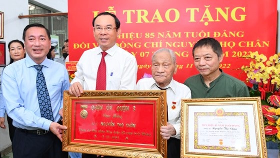 Bí thư Thành ủy TPHCM Nguyễn Văn Nên cùng Bí thư Quận ủy quận 3 Phạm Thành Kiên trao khánh chúc mừng đồng chí Nguyễn Thọ Chân. Ảnh: VIỆT DŨNG