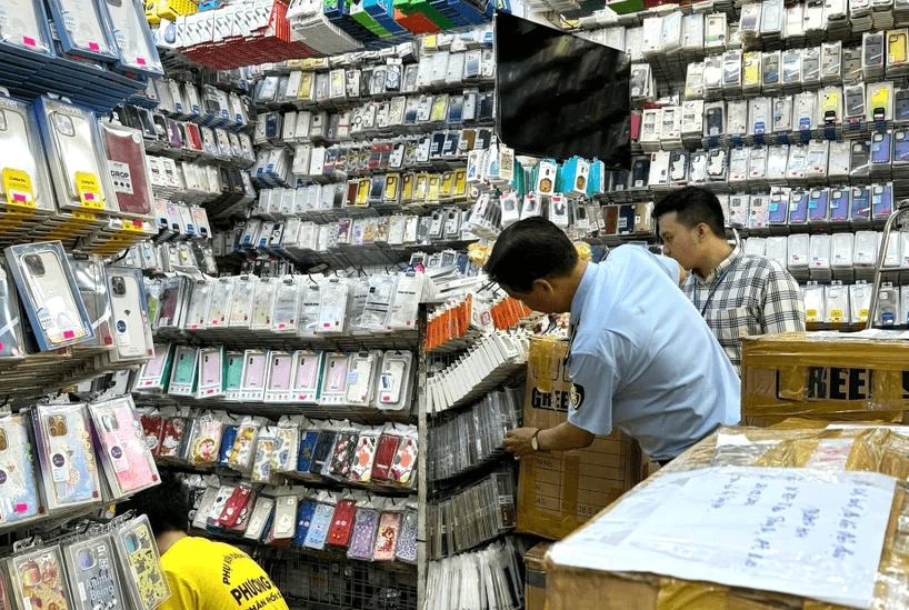 Lực lượng chức năng kiểm tra hộ kinh doanh phụ kiện điện thoại di động. (Ảnh: PV/Vietnam+)