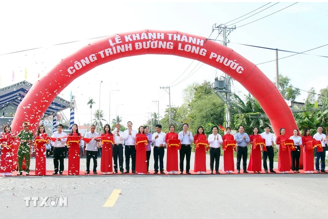 Các đại biểu thực hiện nghi thức khánh thành và đưa vào sử dụng công trình nâng cấp đường Long Phước. (Ảnh: Tiến Lực/TTXVN)