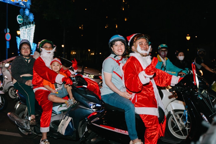 Các gia đình cùng nhau đi dạo phố với trang phục ông già Noel - Ảnh: THANH HIỆP