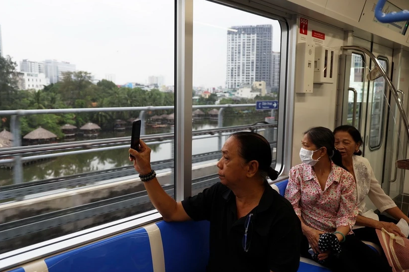 Người dân lưu lại hình ảnh đô thị bên ngoài khi trải nghiệm tuyến metro số 1. (Ảnh: Huyền Trinh/TTXVN)